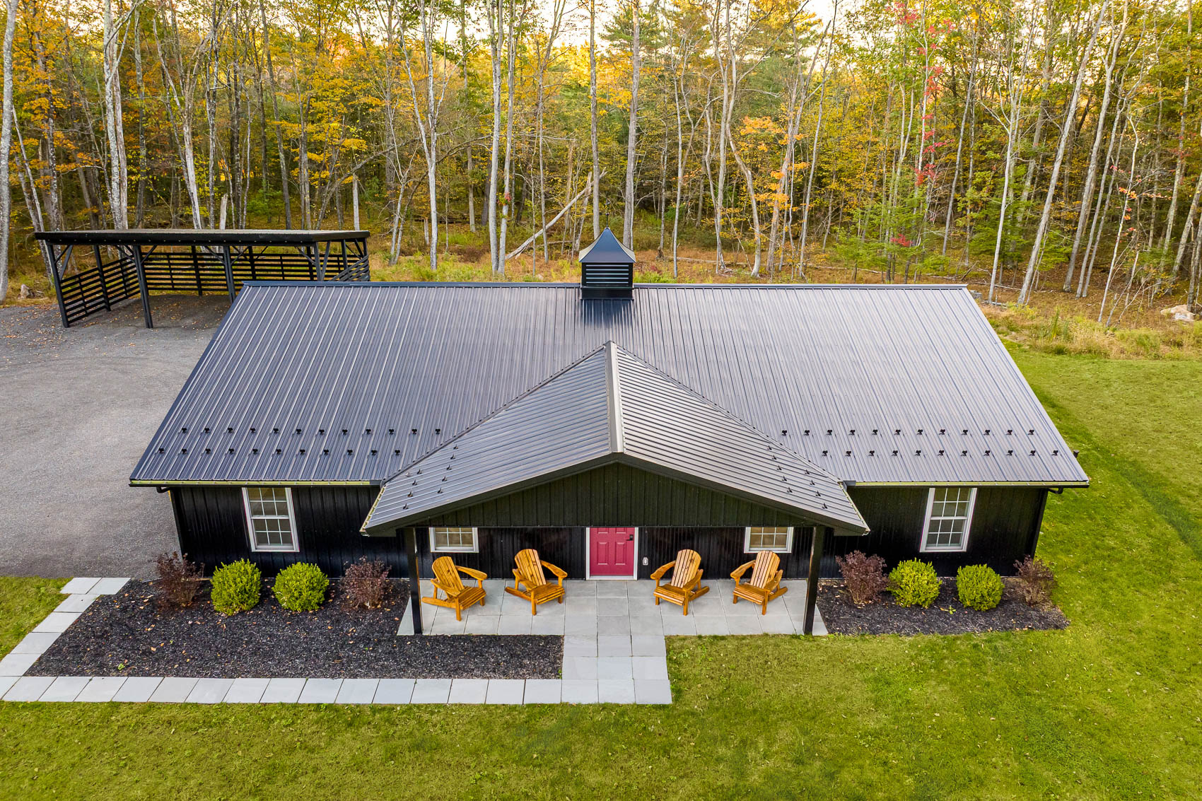 Aerial view of black barndominium home on wooded acreage