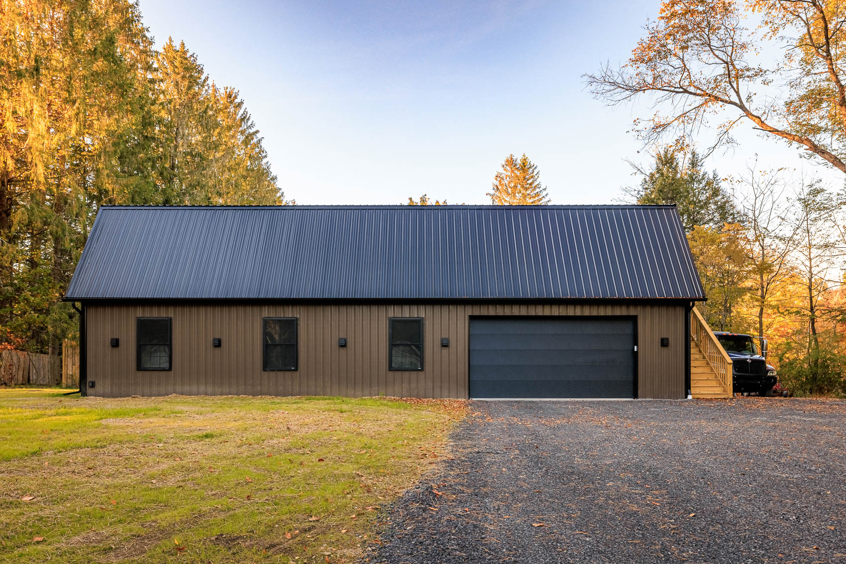 Front elevation of brown gambrel garage with black roof and large bay door