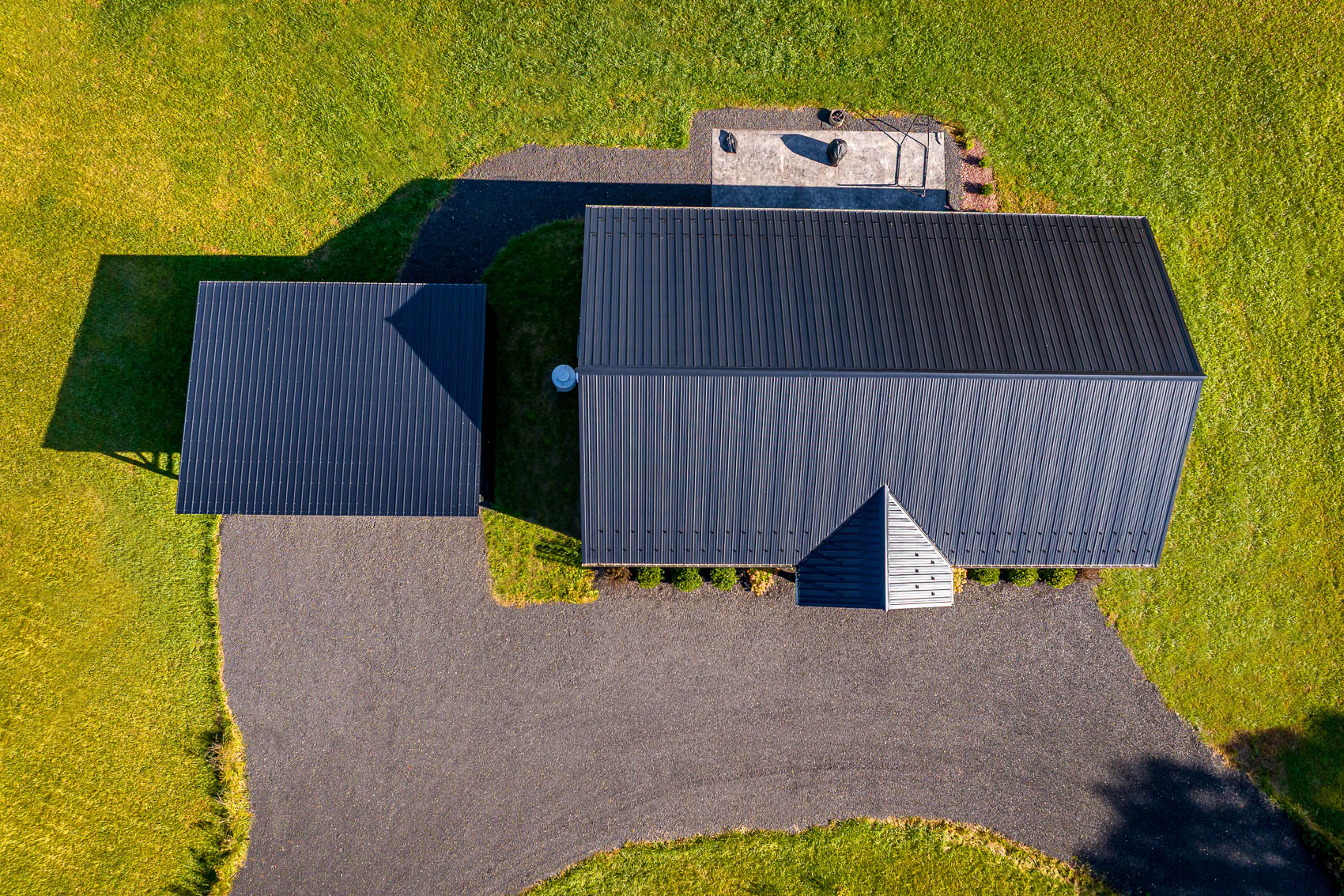 Top-down aerial view of white barndominium roof and covered parking