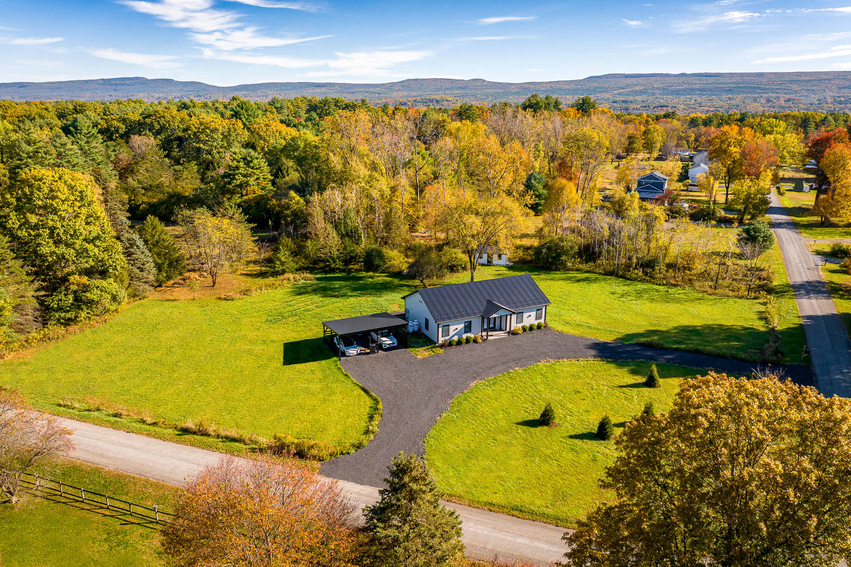 Wide aerial view of white barndominium home on open acreage